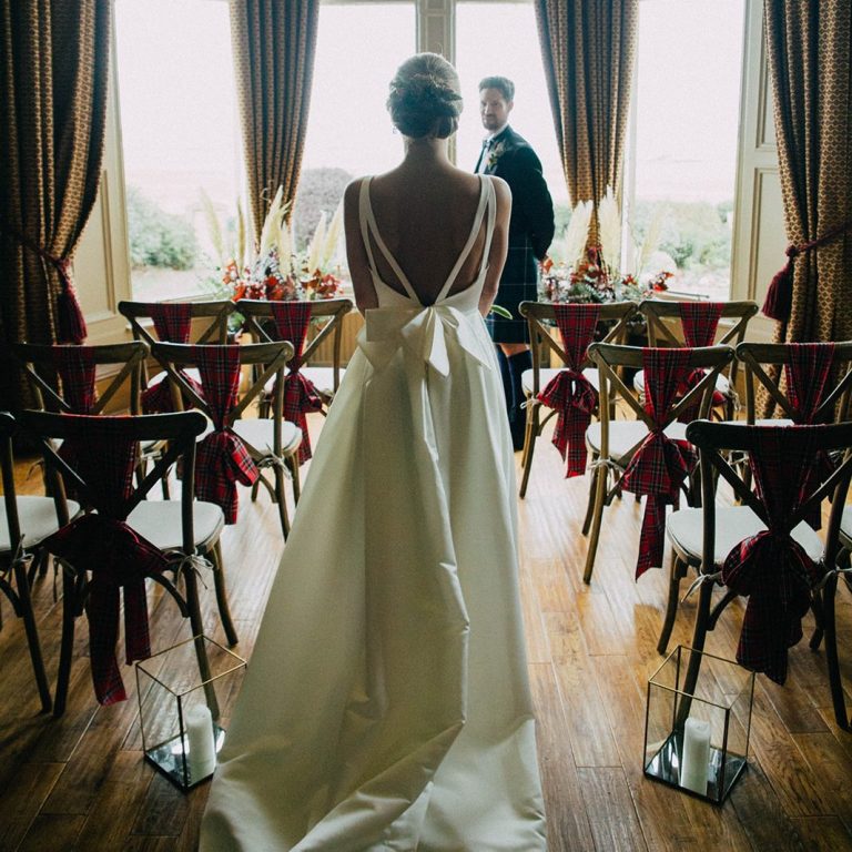Marine Hotel Tartan Ceremony Bride standing in profile, gazing at her groom in a beautifully decorated venue.